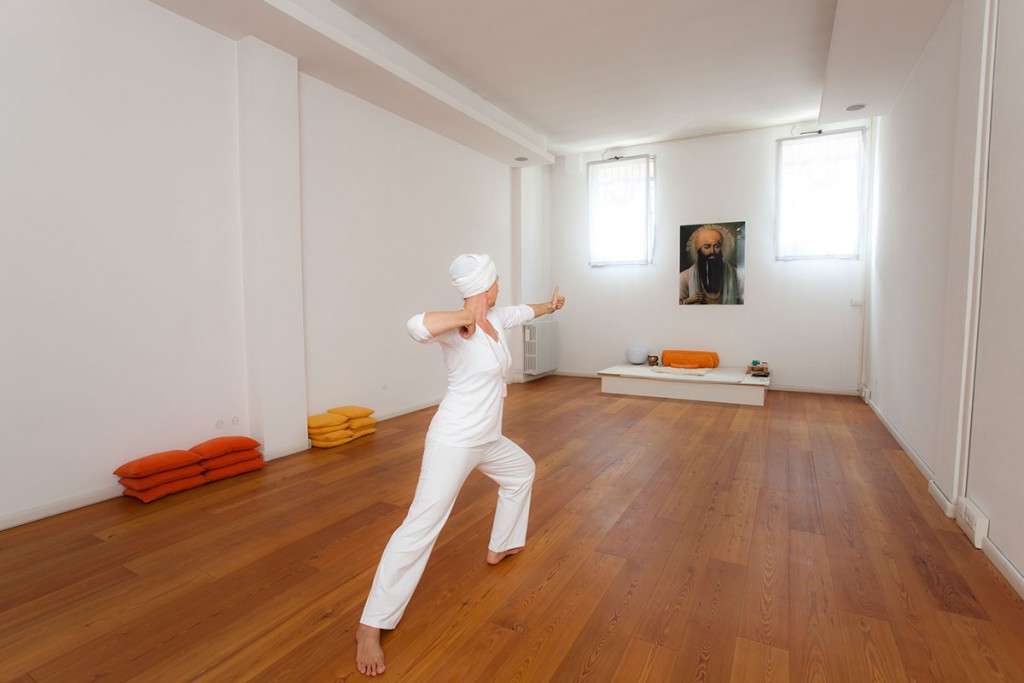 Praticante vestita di bianco esegue un movimento dinamico nella sala del centro